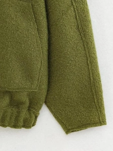 Detail of olive green bomber jacket featuring textured wool fabric and ribbed hem stitching