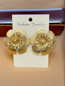 Macro view of gold flower earrings with embossed textures on a fashion jewelry card