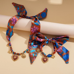 Detail of bohemian silk scarf necklace with golden heart and sunflower pendants