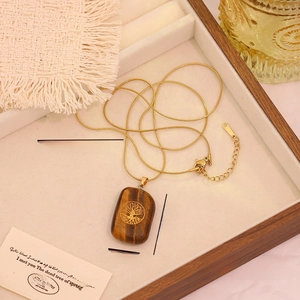 Detail of tiger eye stone pendant with tree of life engraving on a gold snake chain