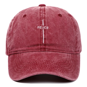 Macro detail of PEACE embroidery and vintage washed red texture on cotton baseball cap