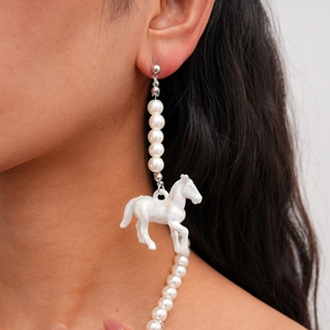 Détail du collier de perles et du pendentif cheval en résine sur un mannequin femme