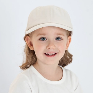 Front view of a little girl wearing a beige cotton baseball cap for sun protection