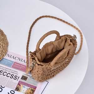Detail of handmade straw crossbody bag with drawstring lining and woven handles