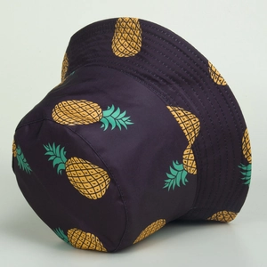 Detailed close-up of navy blue bucket hat featuring vibrant yellow pineapple print pattern