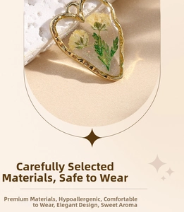 Detail of heart-shaped gold resin pendant with yellow dried flowers and glitter accents