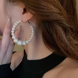 Close-up of elegant gold hoop earrings with gradient pearls on a female model