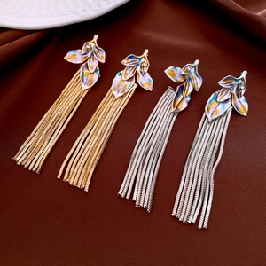 Detail of vintage leaf tassel earrings in gold and silver finish on silk fabric
