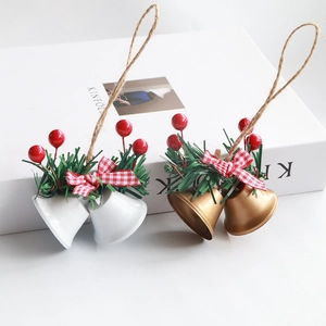 Set of two metal Christmas bells in white and gold with berries and pine needle decor