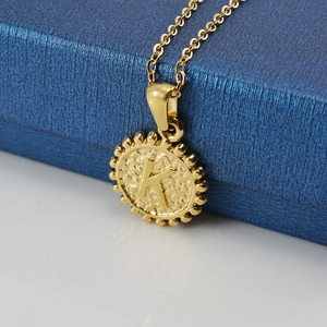 Vue macro du pendentif K doré avec bord perlé et texture martelée sur une boîte bleue