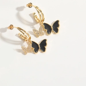 Detail view of gold butterfly earrings with black enamel and sparkling white zircon pavé