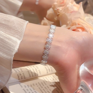 Detailed view of an elegant silver daisy cuff bracelet worn by a model in a cozy setting