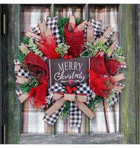 Close-up of Merry Christmas wooden plaque on a festive wreath with ribbons and berries