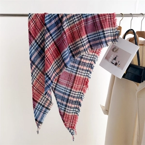 Detail of red and blue checkered cashmere-like scarf with fringe hanging on a rack