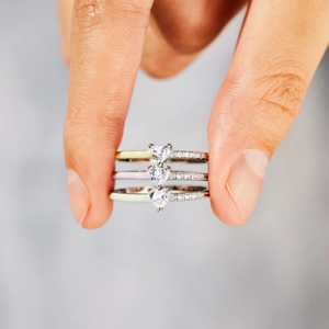 Three stacked heart rings with pastel enamel and pavé crystals on polished silver bands