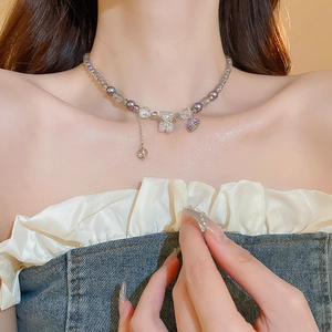 Detail of beaded necklace featuring purple heart and transparent bear charms on neck