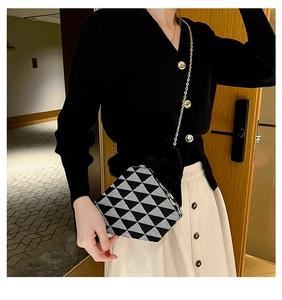 Detail of a geometric black and white knit bag with faux fur handle and gold chain