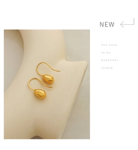 Detailed view of polished teardrop-shaped gold-plated earrings with minimalist hook design