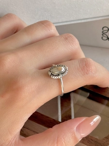 Detailed view of an oval silver ring featuring vintage rope textures and retro artisan style