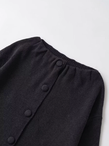 Gros plan d'un cardigan noir en maille avec texture verticale et boutons recouverts