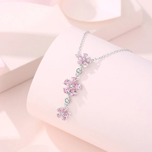 S925 silver necklace with three pink plum blossom pendants on a soft pink background