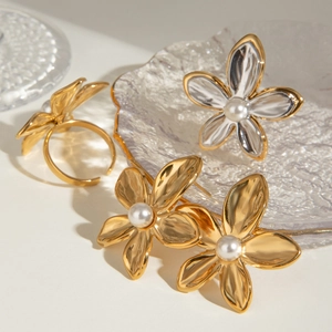 Detailed set of gold flower jewelry featuring smooth white pearls on a glass tray