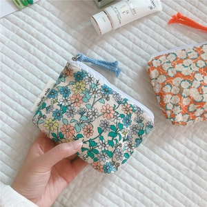 Close-up of floral cotton mini coin purse with simple wish label and blue zipper pull