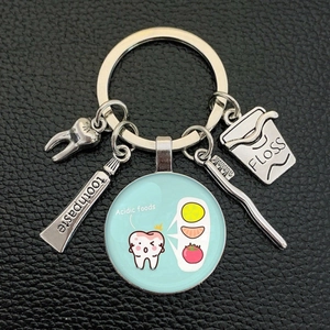 Creative metal keychain set featuring a tooth, toothbrush, and floss on a dark background