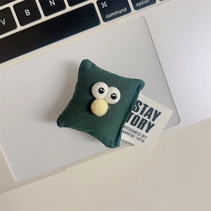 Macro view of dark green plush monster phone stand with big eyes and yellow puff ball