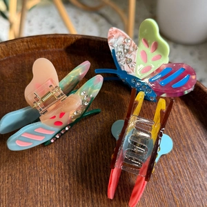 Detail of acetate butterfly hair claws with rhinestones on a wooden tray