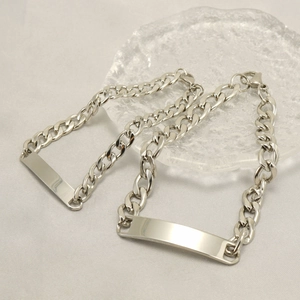 Close-up of silver stainless steel Cuban ID bracelet with rectangle plate on glass tray