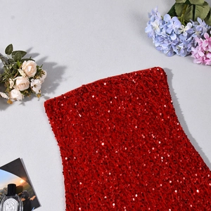Détail de la texture à paillettes rouges avec fleurs et flacon de parfum en décor