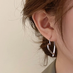 Nahaufnahme von minimalistischen silbernen Herz-Ohrringen an einem weiblichen Model