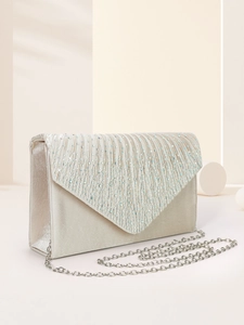 Detail of champagne satin evening clutch featuring pleated texture and V-shape rhinestone flap