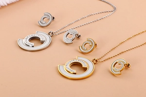 Detailed view of C-shaped necklaces and stud earrings set with shell inlay and diamonds