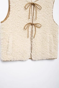 Detail of cream fleece vest featuring contrast khaki piping and front tie closures