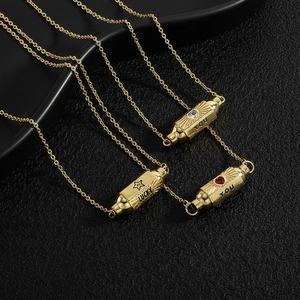 Detailed close-up of golden capsule pendants with Lucky and You engravings and red heart