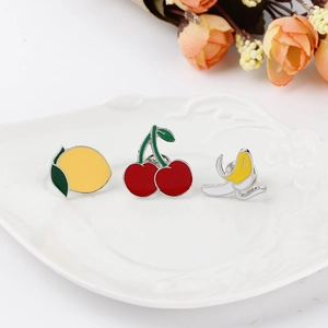 Detailed close-up of vibrant enamel fruit brooches featuring lemon, cherry, and banana on a plate