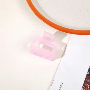 Detailed view of a pink matte square hair claw clip styled on a magazine background