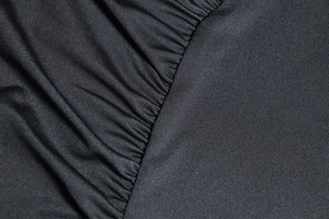 Macro detail of high-density black fabric showing fine pleating and smooth texture