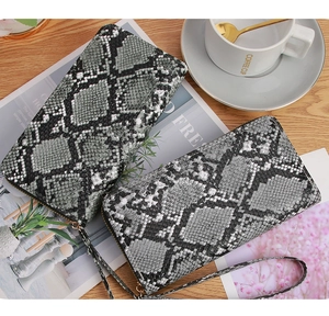 Top view of two snakeskin pattern zip-around wallets with wristlet on a wooden table