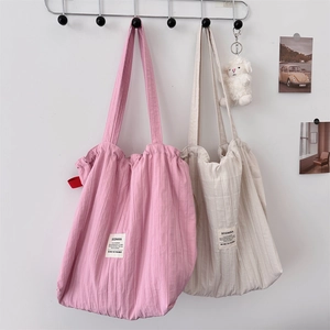 Detailed close-up of striped canvas tote bags in pink and beige on wall hooks