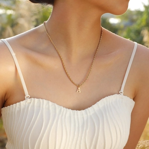 Detail shot of a golden stainless steel letter A pendant on a twisted rope chain necklace