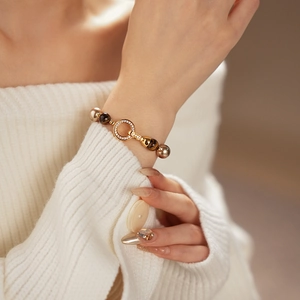 Close-up of vintage tiger eye and pearl gold-plated bracelet worn on a white sweater