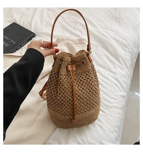 Detail of straw bucket bag featuring brown leather drawstring and woven texture
