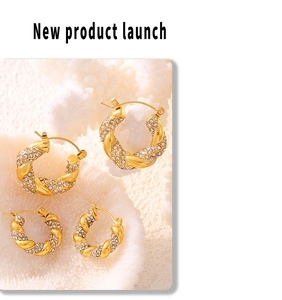 Macro shot of gold twist hoop earrings with pavé zircons on white coral display