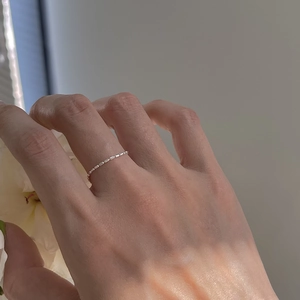 Close-up of a 925 silver minimalist adjustable chain ring on a finger with flowers