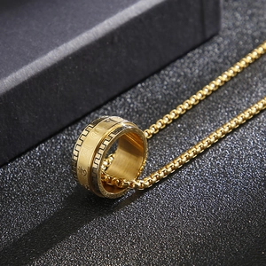 Detail view of a gold stainless steel mantra spinning ring on a box chain necklace