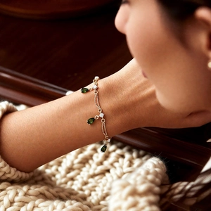 Detail von 18k vergoldetem Armband mit grünen Tropfenanhängern und kleinen Diamanten