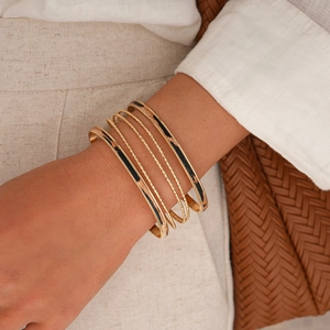 Dettaglio di bracciali multistrato dorati con stampa leopardata sul polso di una donna